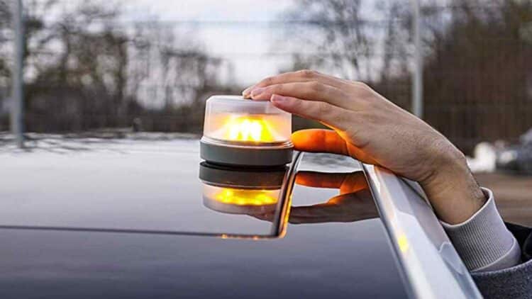 Conductor colocando luz de emergencia V16 en el techo del coche.