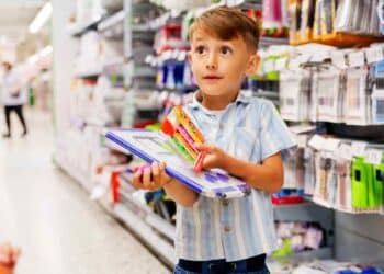 Niño comprando material escolar en supermercado durante la vuelta al cole.