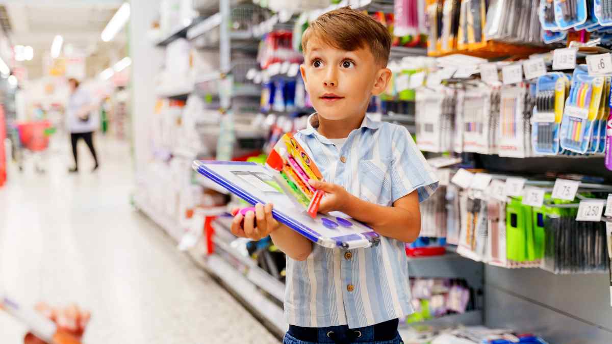 Niño comprando material escolar en supermercado durante la vuelta al cole.