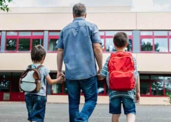 Padre llevando a sus hijos al colegio en la vuelta al cole.