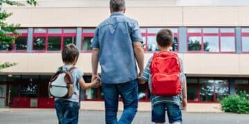 Padre llevando a sus hijos al colegio en la vuelta al cole.