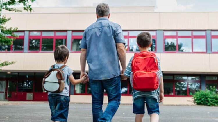 Padre llevando a sus hijos al colegio en la vuelta al cole.