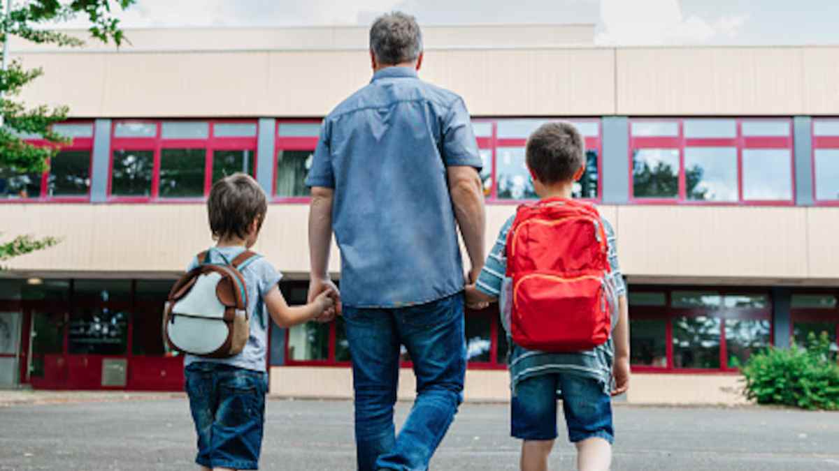 Padre llevando a sus hijos al colegio en la vuelta al cole.