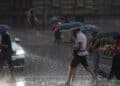 Personas con paraguas bajo fuerte tormenta en el Mediterráneo con riesgo de inundaciones.