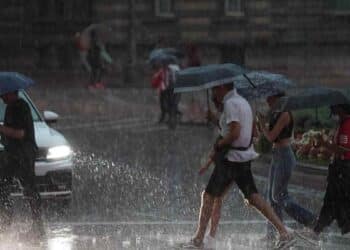 Personas con paraguas bajo fuerte tormenta en el Mediterráneo con riesgo de inundaciones.
