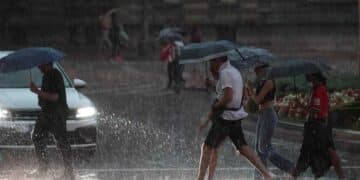 Personas con paraguas bajo fuerte tormenta en el Mediterráneo con riesgo de inundaciones.
