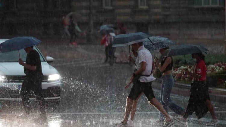 Personas con paraguas bajo fuerte tormenta en el Mediterráneo con riesgo de inundaciones.