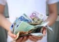 Persona con billetes de euros representando ayudas del SEPE y nuevo tope de ingresos 2025.
