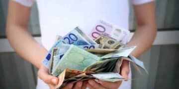 Persona con billetes de euros representando ayudas del SEPE y nuevo tope de ingresos 2025.