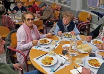 Personas mayores en un comedor municipal de Madrid compartiendo comida.