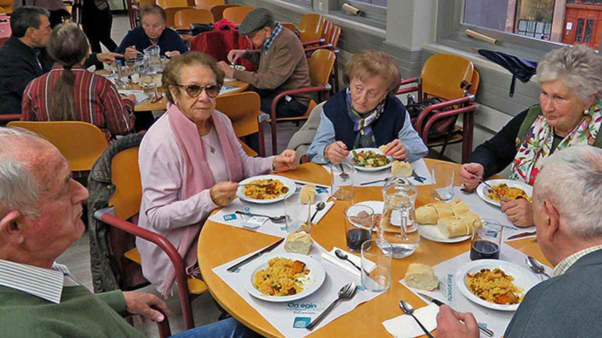 Personas mayores en un comedor municipal de Madrid compartiendo comida.