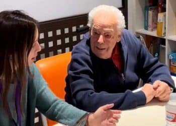 Voluntaria joven conversa con un mayor en taller de Cruzando Caminos en Madrid.