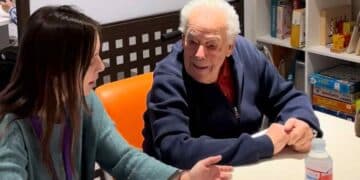 Voluntaria joven conversa con un mayor en taller de Cruzando Caminos en Madrid.