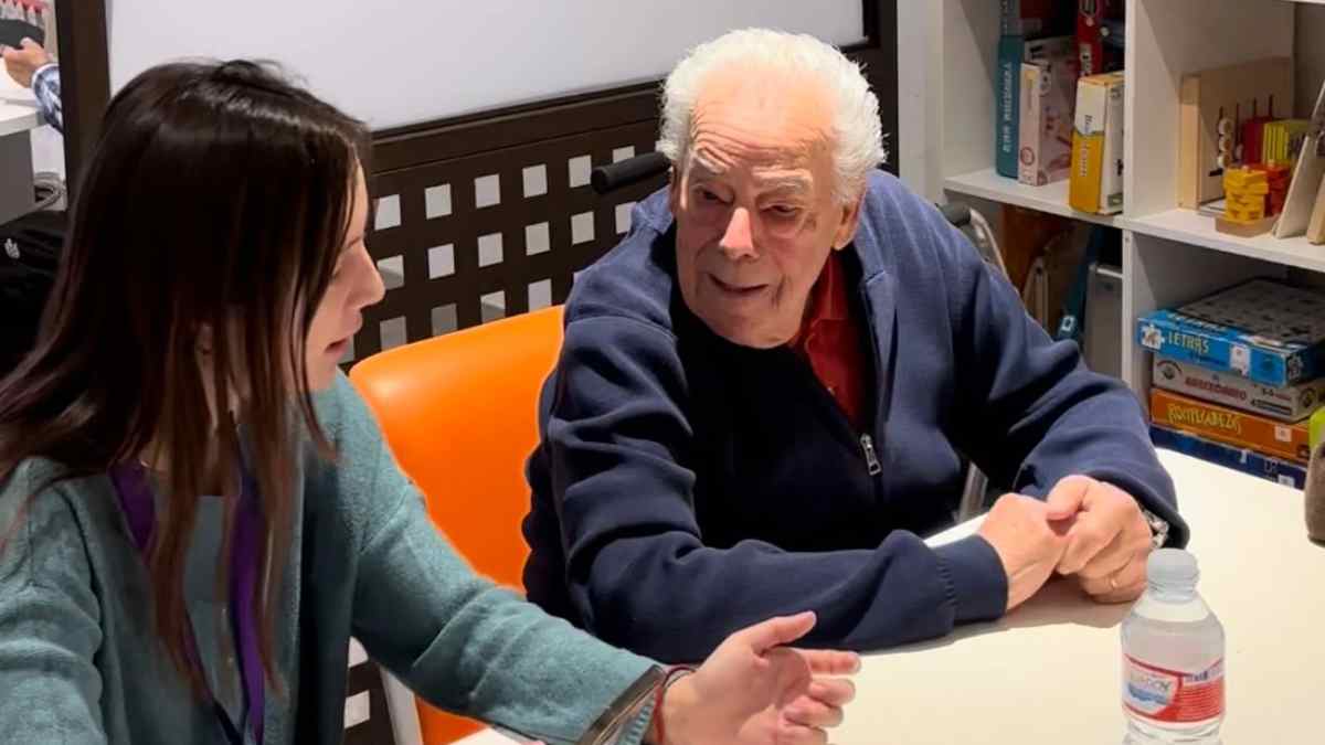 Voluntaria joven conversa con un mayor en taller de Cruzando Caminos en Madrid.