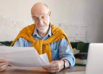 Hombre mayor revisando papeles sobre jubilación anticipada de mutualistas anteriores a 1967.