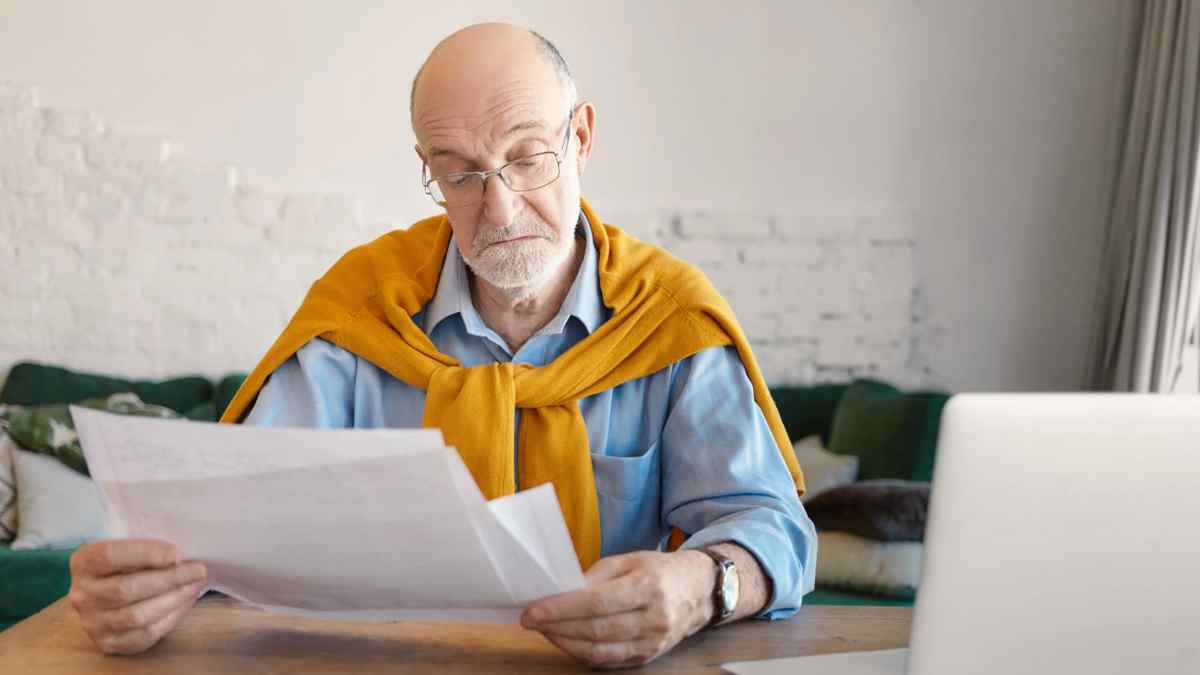 Hombre mayor revisando papeles sobre jubilación anticipada de mutualistas anteriores a 1967.