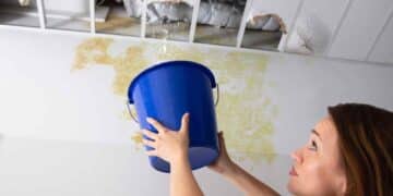 Mujer colocando un cubo bajo gotera en el techo según la Ley de Propiedad Horizontal.