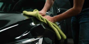 Persona limpiando un coche en concesionario de Madrid con paño de microfibra verde.