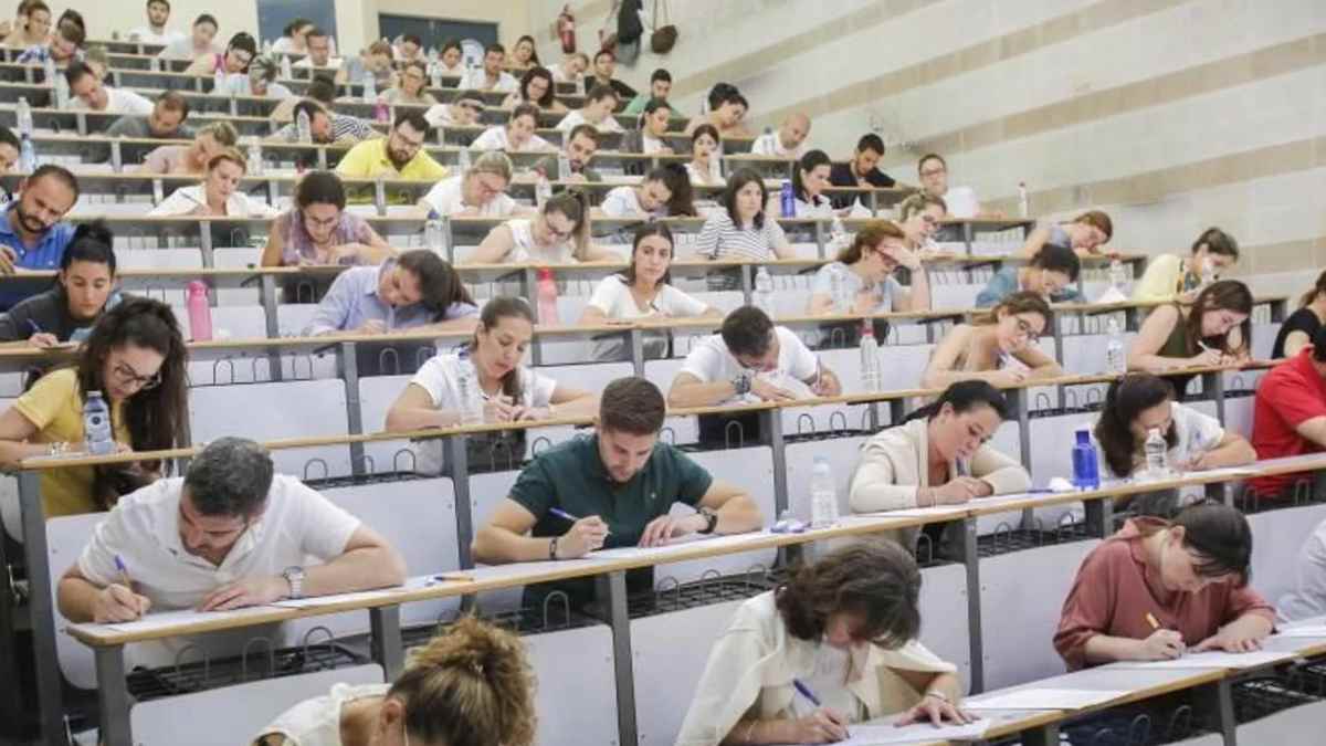 Personas realizando examen de oposiciones en un aula universitaria.