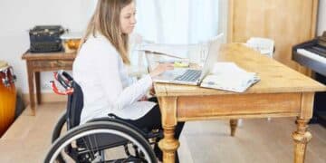 Mujer en silla de ruedas trabajando con portátil sobre pensión de incapacidad permanente.