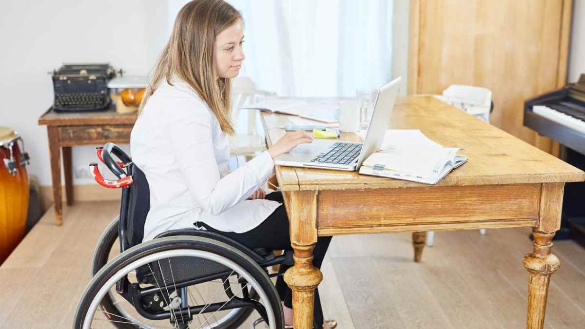 Mujer en silla de ruedas trabajando con portátil sobre pensión de incapacidad permanente.