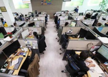 Empleados en oficina de atención al cliente antes de los despidos de Salesforce por la automatización con IA.
