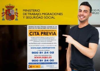 Trabajador del SEPE señalando cartel de cita previa.
