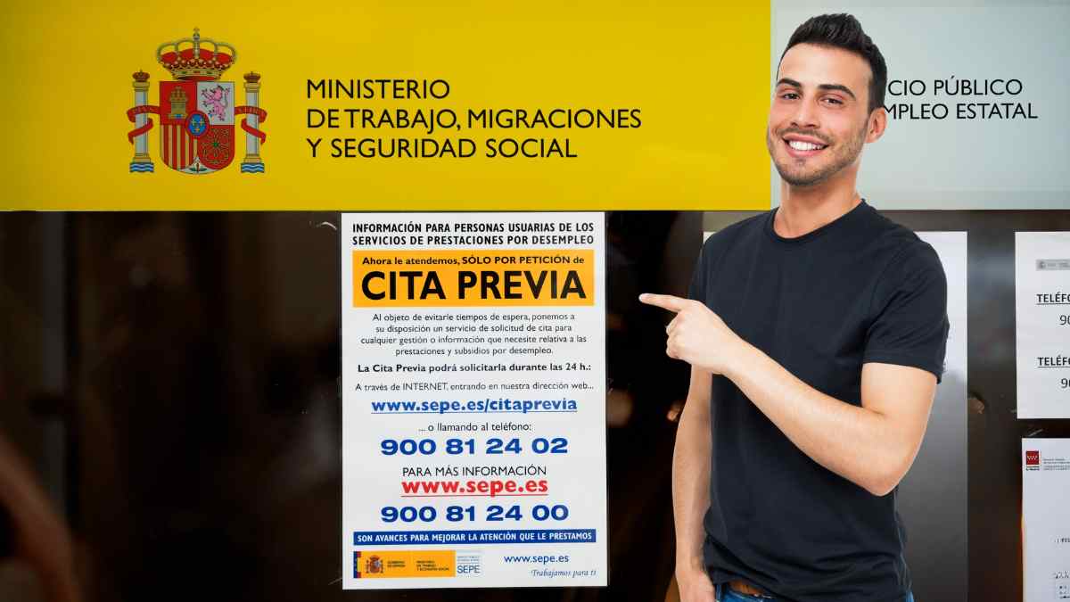 Trabajador del SEPE señalando cartel de cita previa.