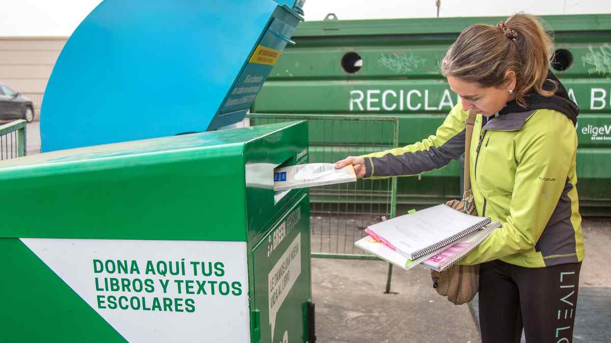 Mujer reciclando libros de texto para conseguir descuento con BOOKCYCLE en la vuelta al cole 2025