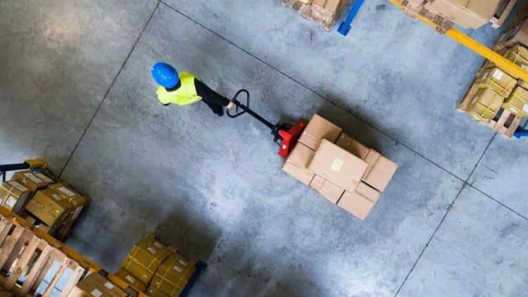 Mozo de almacén en Pinto usando transpaleta para mover cajas.