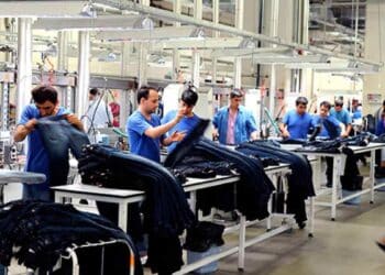 Trabajadores manipulando prendas textiles en una fábrica de Alcalá de Henares para oferta de empleo de Adecco.