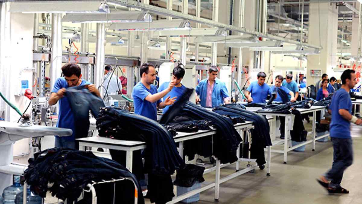 Trabajadores manipulando prendas textiles en una fábrica de Alcalá de Henares para oferta de empleo de Adecco.