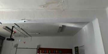 Aula con grietas y filtraciones en el techo de un colegio público de Madrid durante las reformas educativas de 2025.