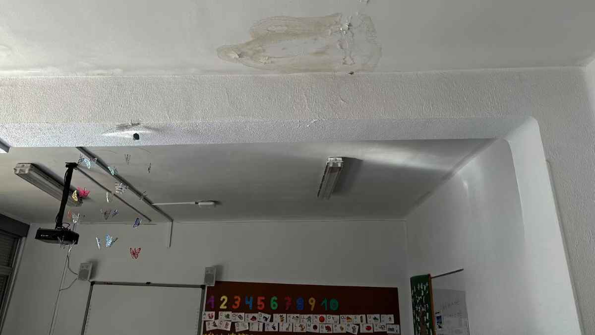 Aula con grietas y filtraciones en el techo de un colegio público de Madrid durante las reformas educativas de 2025.