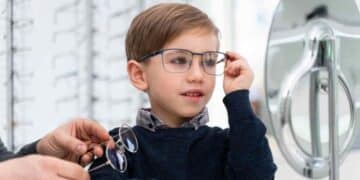 Niño probándose gafas en óptica por la ayuda de 100 euros para gafas infantiles en España.