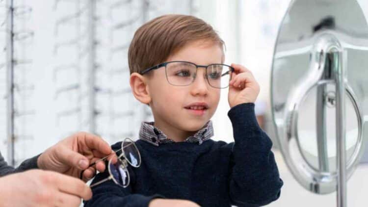Niño probándose gafas en óptica por la ayuda de 100 euros para gafas infantiles en España.