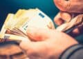 Persona contando billetes de euro representando la ayuda económica de la Seguridad Social para nacidos entre 1960 y 2002.