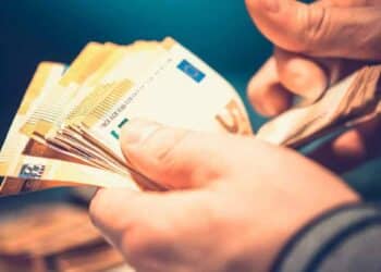 Persona contando billetes de euro representando la ayuda económica de la Seguridad Social para nacidos entre 1960 y 2002.