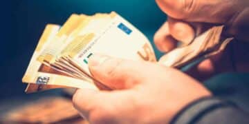 Persona contando billetes de euro representando la ayuda económica de la Seguridad Social para nacidos entre 1960 y 2002.