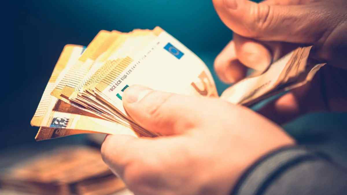 Persona contando billetes de euro representando la ayuda económica de la Seguridad Social para nacidos entre 1960 y 2002.