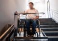 Persona en silla de ruedas usando plataforma salvaescaleras en vivienda adaptada en Alcorcón.