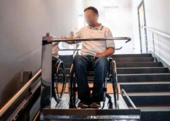 Persona en silla de ruedas usando plataforma salvaescaleras en vivienda adaptada en Alcorcón.