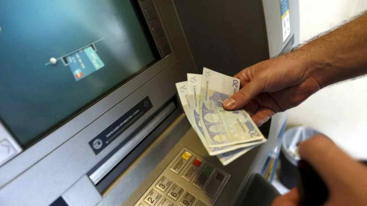 Persona retirando dinero en cajero automático tras nueva norma europea sobre verificación de nombre e IBAN en transferencias.