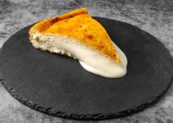 Porción de tarta de queso cremosa de Bascake Madrid sobre base de pizarra negra.