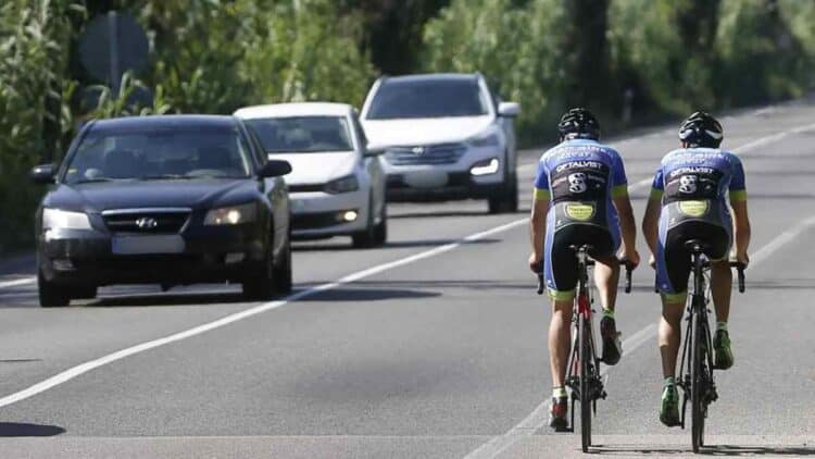 Ciclistas circulando por carretera junto a coches tras cambio de la DGT publicado en el BOE.