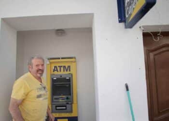 Hombre junto a cajero automático multimarca en un pueblo