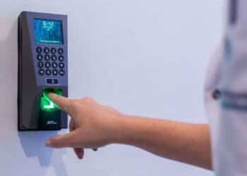 Persona fichando con huella digital en registro horario laboral según el Estatuto de Trabajadores.