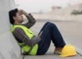 Trabajador agotado en pausa laboral, Estatuto de los Trabajadores garantiza descansos diarios y semanales mínimos.