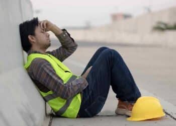 Trabajador agotado en pausa laboral, Estatuto de los Trabajadores garantiza descansos diarios y semanales mínimos.