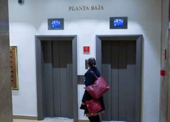 Mujer esperando el ascensor en la planta baja de una comunidad de vecinos